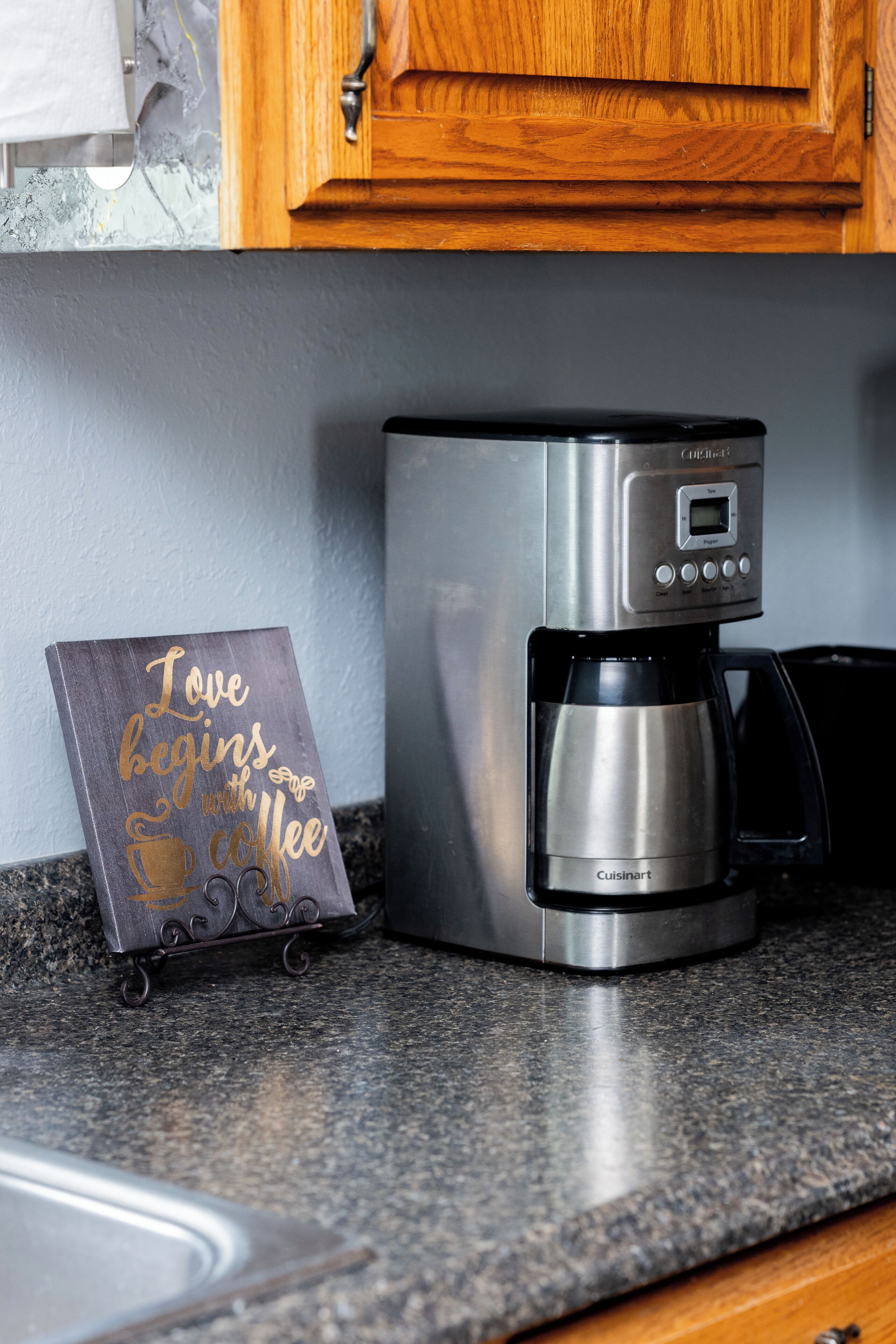 Une cuisine équipée d’une machine à café et d’une pancarte sur laquelle on peut lire : « L’amour commence avec un café. »