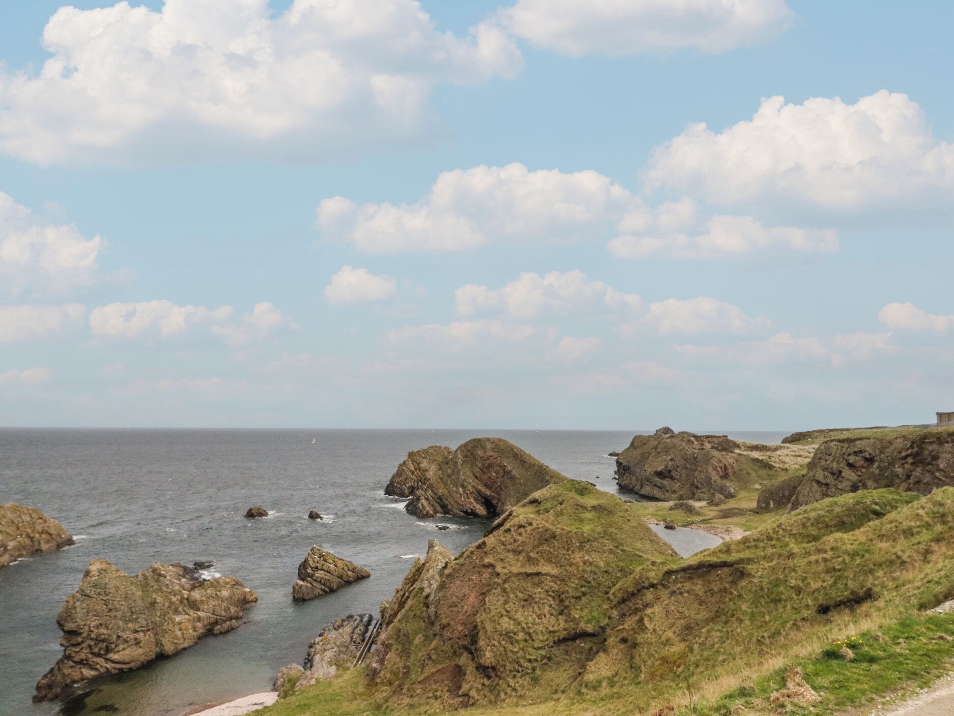 A coastal landscape with rocky outcrops and grassy terrain.