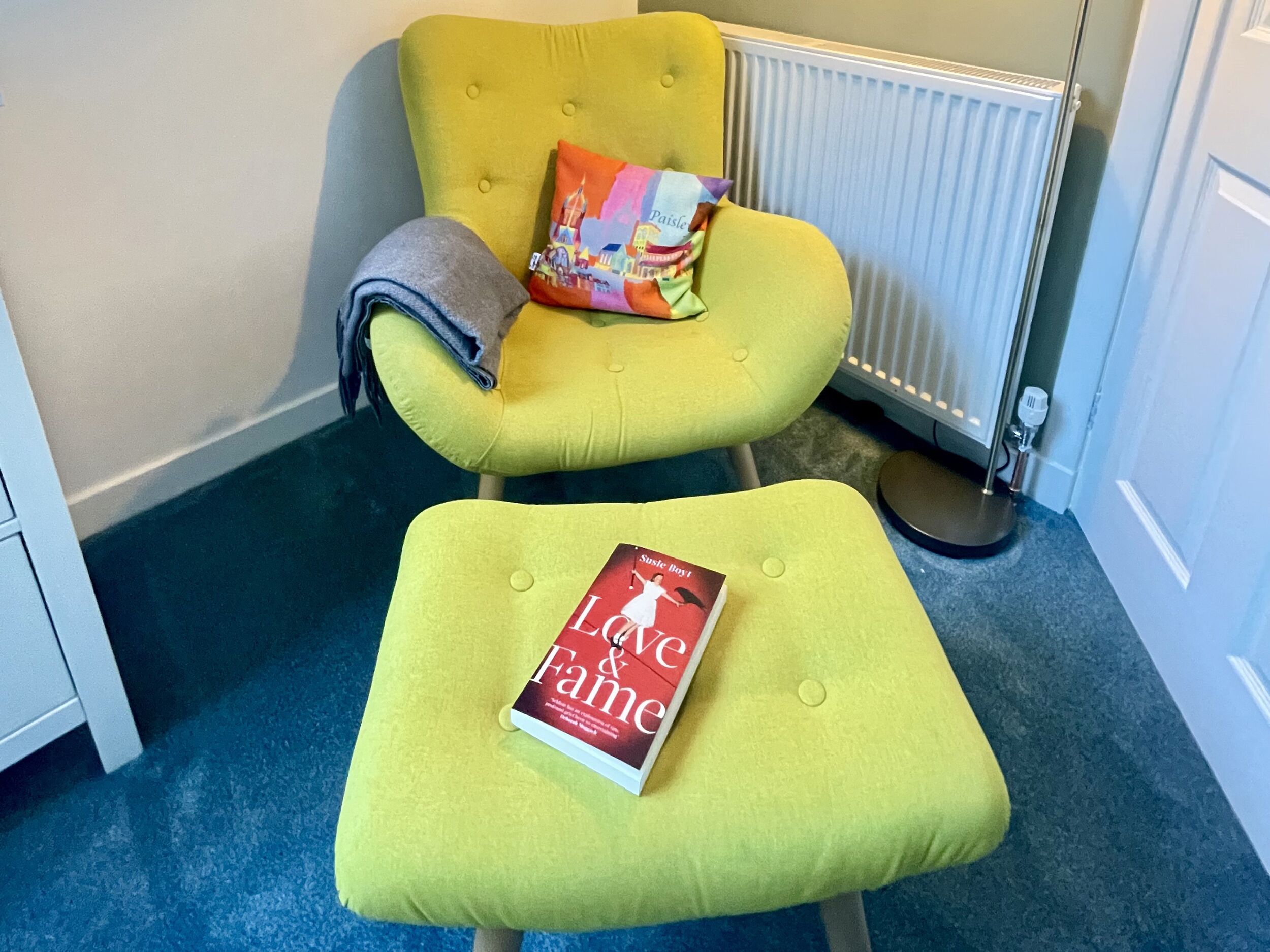 A yellow armchair with a book titled "Love & Family" on a matching ottoman.
