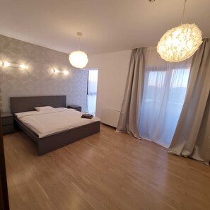 A modern bedroom with a large bed, a nightstand, a wall-mounted light, and a ceiling light fixture.