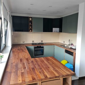 A modern kitchen with a wooden countertop, built-in oven, and a sink.