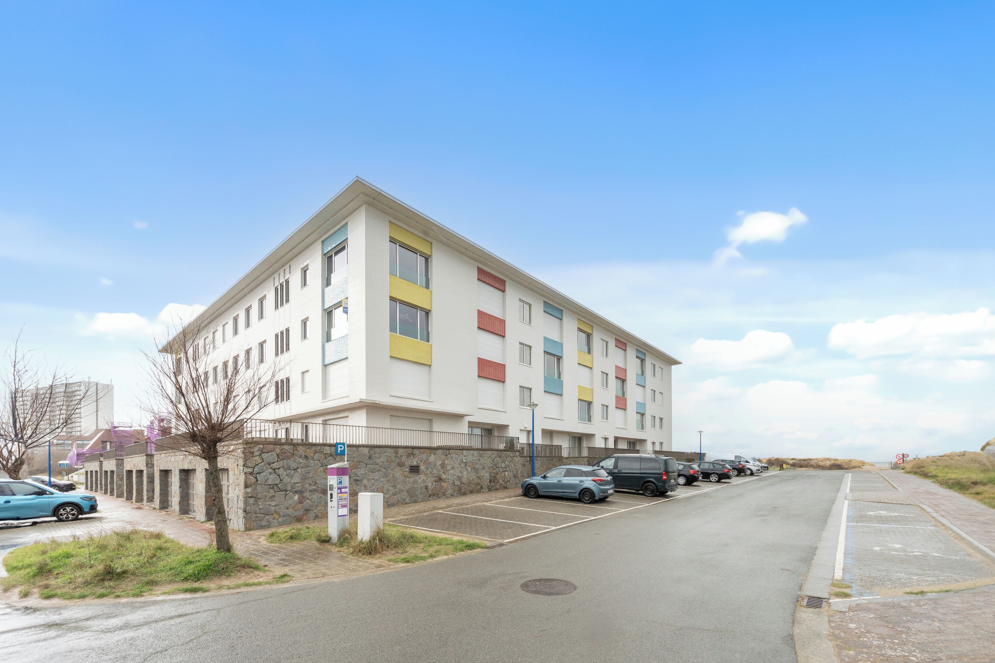 Un immeuble à plusieurs étages avec un parking situé devant.