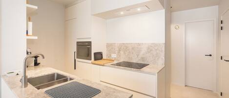 A modern kitchen with a double sink, a built-in oven, and a countertop with a mat.