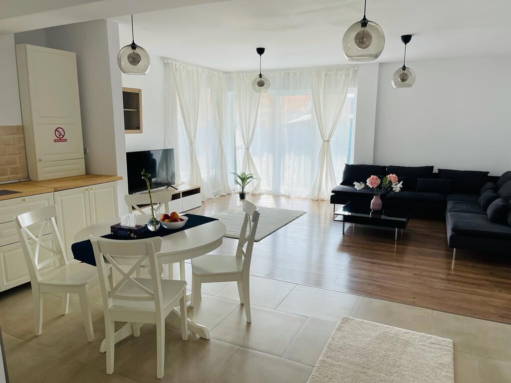 Ein modernes Wohnzimmer mit Essbereich, einem schwarzen Sofa und einem Fernseher.