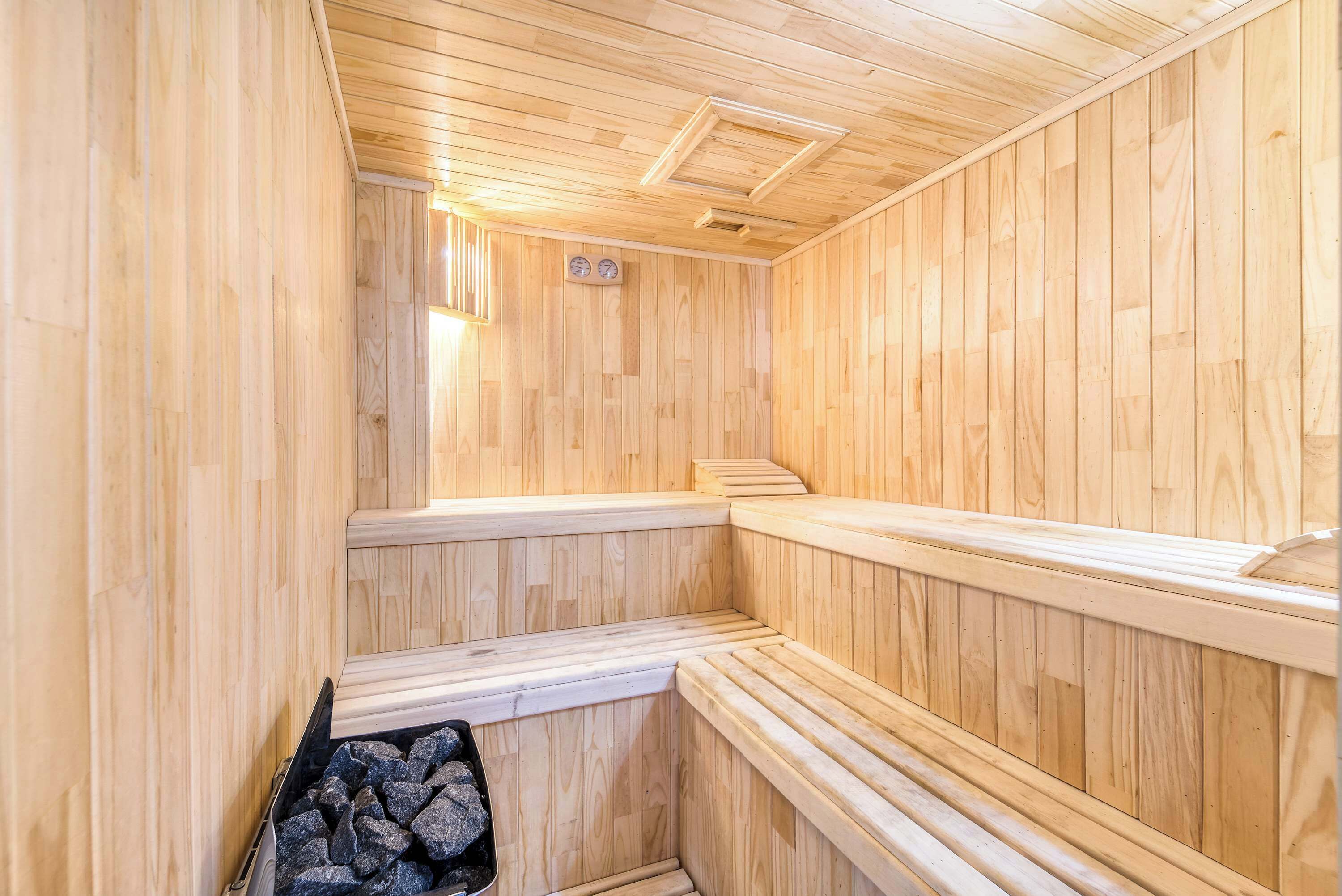 Eine Sauna mit Holzwänden und -bänken, einem sichtbaren Ofen und einer Uhr an der Wand.