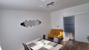 A modern living room with a dining table, a sofa, and a built-in wardrobe. - Modern & bright 3-room apartment | Wuppertal & Netflix (Wuppertal)