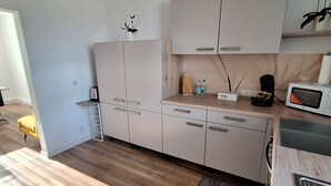 A modern kitchen with white cabinets, a wooden countertop, and a microwave. - Modern & bright 3-room apartment | Wuppertal & Netflix (Wuppertal)