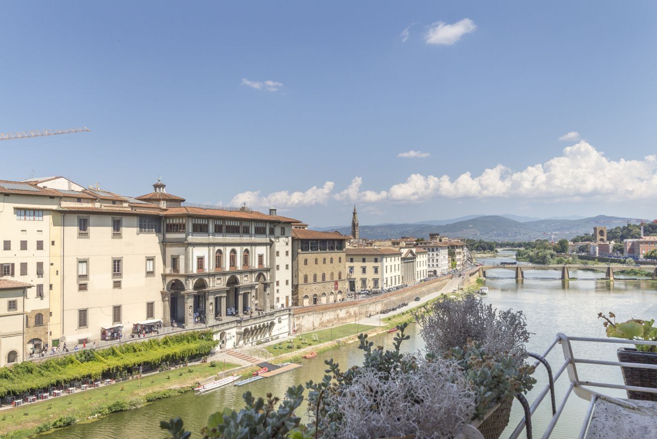 A riverside view of historic buildings with a bridge in the background.