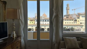 Una habitació amb una finestra gran, televisió, làmpada i un llit.