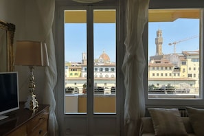 A room with a large window, a television, a lamp, and a bed. - Wonderful terrace over Ponte Vecchio w/lift (Firenze)