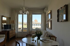 Ein Zimmer mit Esstisch, Stühlen, einer Chandelierleuchtre, einem Fernseher und Blick auf eine Kuppel durch große Fenster.