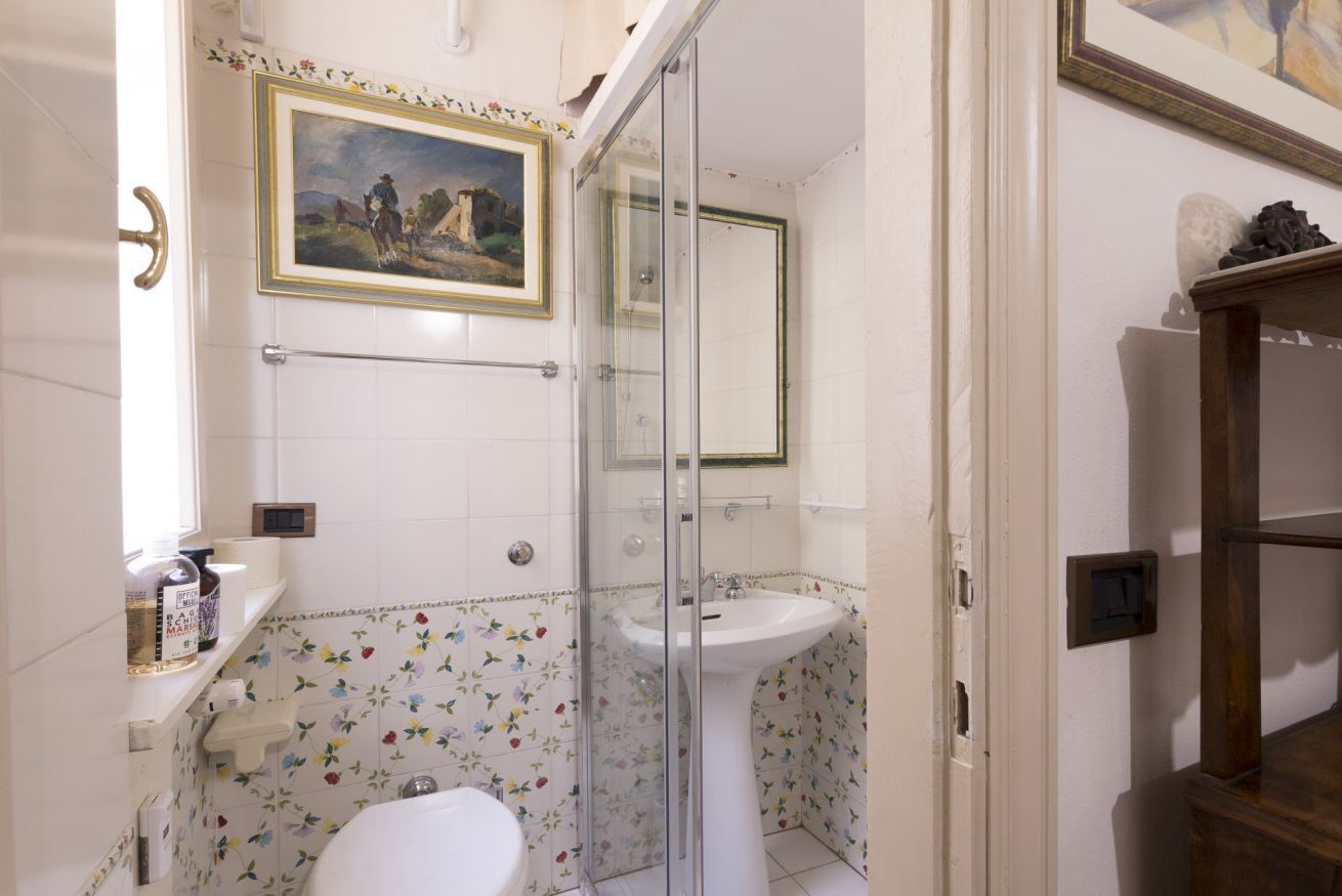 Een badkamer met een glazen douchecabine, een wastafel op voet en een toilet.