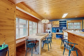 Interior de una cabaña de madera con comedor, cocina y estanterías empotradas.