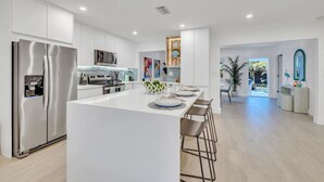 Cozinha moderna com ilha central, eletrodomésticos de aço inoxidável e vista para um jardim.