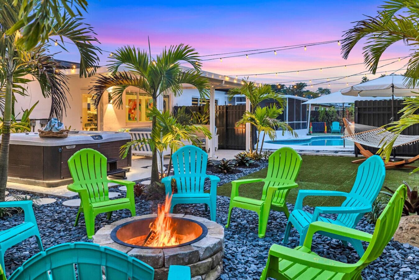 Un patio trasero con una chimenea, mobiliario exterior, una piscina y una casa.