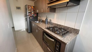 A modern kitchen with wooden cabinets, a stainless steel refrigerator, a gas stove, and a dishwasher. - View + Swimming Pool Fast WiFi | 100 Meters subway". (Sabaneta)