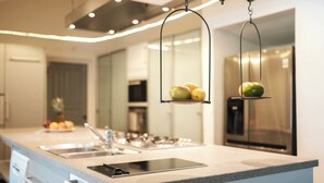 Una cocina moderna con una isla grande, electrodomésticos de acero inoxidable y una exhibición colgante de frutas.