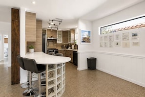 A modern kitchen with a curved bar area, built-in cabinets, and a wall-mounted trash can. - Entire Home Heated Pool Just Minutes from Hollywood Beach and Hard Rock Stadium (Hollywood)