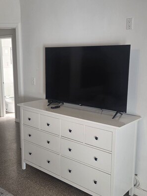 A white dresser with a flat-screen TV on top, a remote control, and a power outlet on the wall. - Private Pool • Sleeps 8 • Near Beach, Downtown Hollywood, Stadium Events & FLL airport (Hollywood)