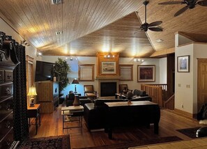 A cozy living room with a fireplace, comfortable seating, and a ceiling fan.