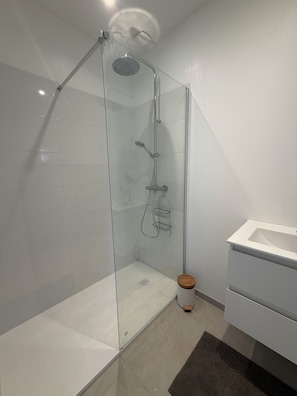 A modern bathroom with a glass-enclosed shower, a white sink, and a wooden stool. - Cosy house with garden, quiet, near beach & port (paimpol)