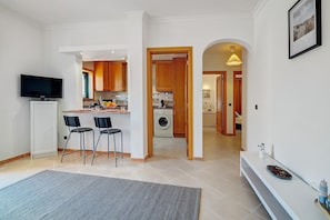 Una cocina moderna con armarios de madera, lavadora integrada y un comedor con dos sillas.
