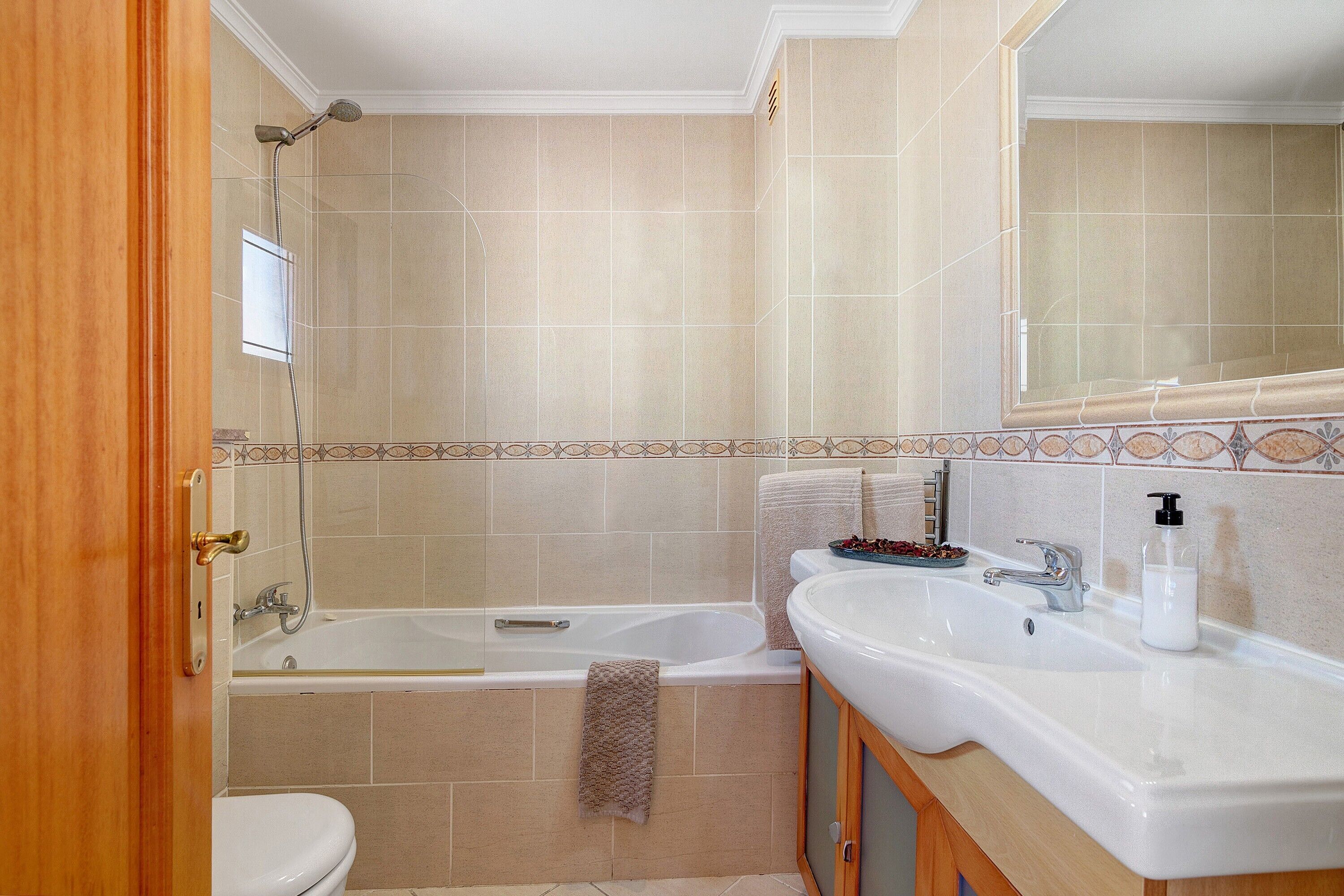 Een badkamer met bad, toilet, wastafel en spiegel.
