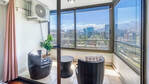 Un balcone con vista sulla città, un ventilatore a soffitto e mobili in vimini.