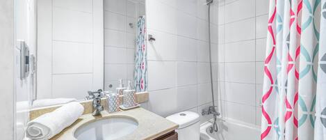 A modern bathroom with a sink, toilet, shower, and a large mirror.