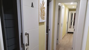 A hallway with a white door marked with an 'A', a mirror, and a light-colored tiled floor. - Full apartment 13 beds and 3 bathrooms near the airport North La Laguna Tenerife (La Laguna)