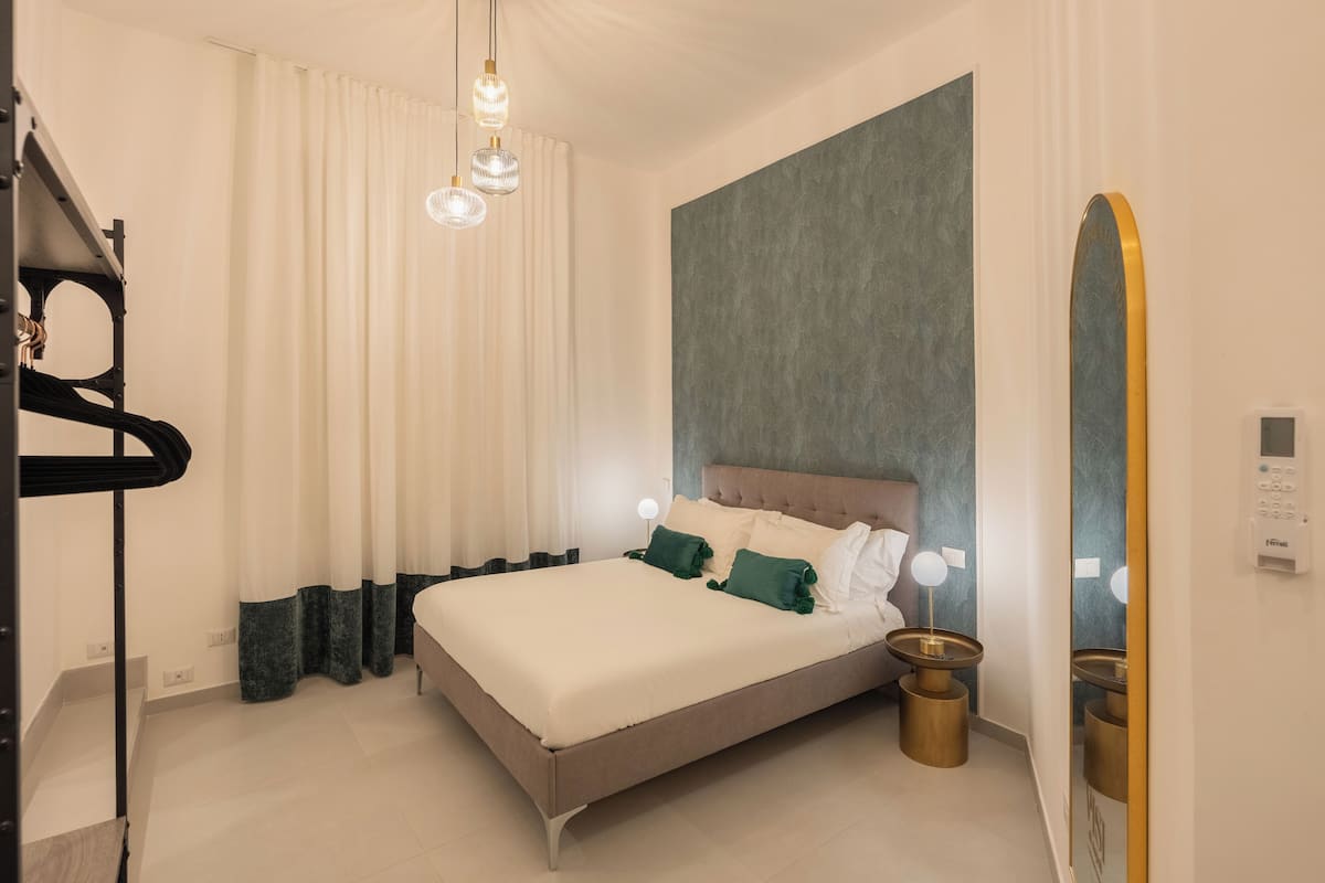 A modern bedroom with a bed, curtains, a wall-mounted mirror, and bedside lamps.