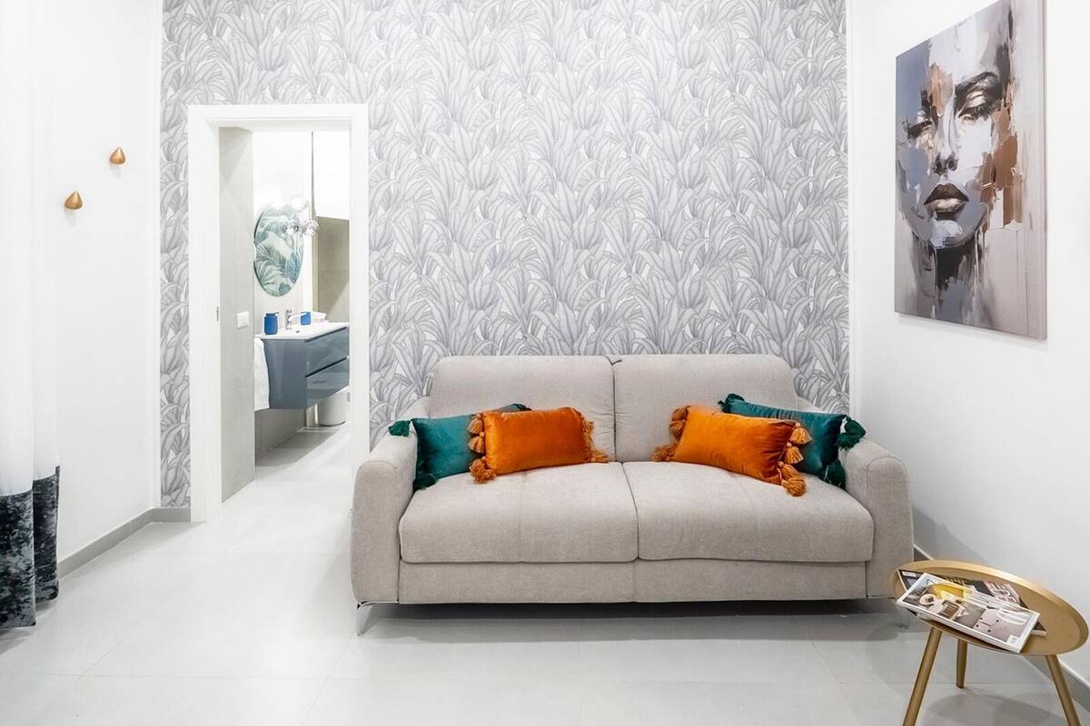 A living room with a sofa, a small table, and a wall with a leaf pattern.