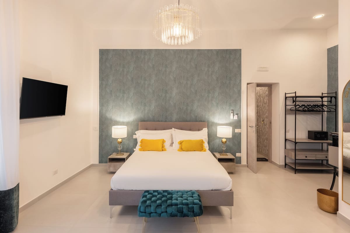 A modern bedroom with a large bed, bedside lamps, a TV, and a wardrobe.