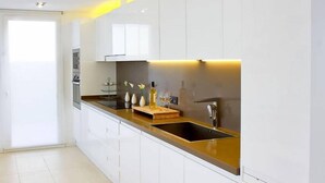 A modern kitchen with white cabinets, a black countertop, and a stainless steel sink. - Villa Bettina - Charming Interior Spaces (San Jaime Mediterráneo)