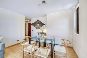Un comedor con una mesa de vidrio, sillas de mimbre y una lámpara colgante.