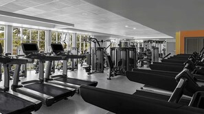 Un gimnasio con cintas de correr, máquinas de pesas y colchonetas de ejercicio.