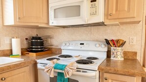 Une cuisine avec un four blanc, un four à micro-ondes placé au-dessus, et des armoires en bois.