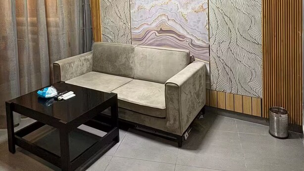 A modern living room with a sofa, a glass coffee table, and a chandelier. - spira.staycation (Noida)