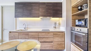 A modern kitchen with dark wood cabinets, a stainless steel sink, and a built-in oven. - Live Ñuñoa: conexión L1/L3 y vida urbana (Ñuñoa)