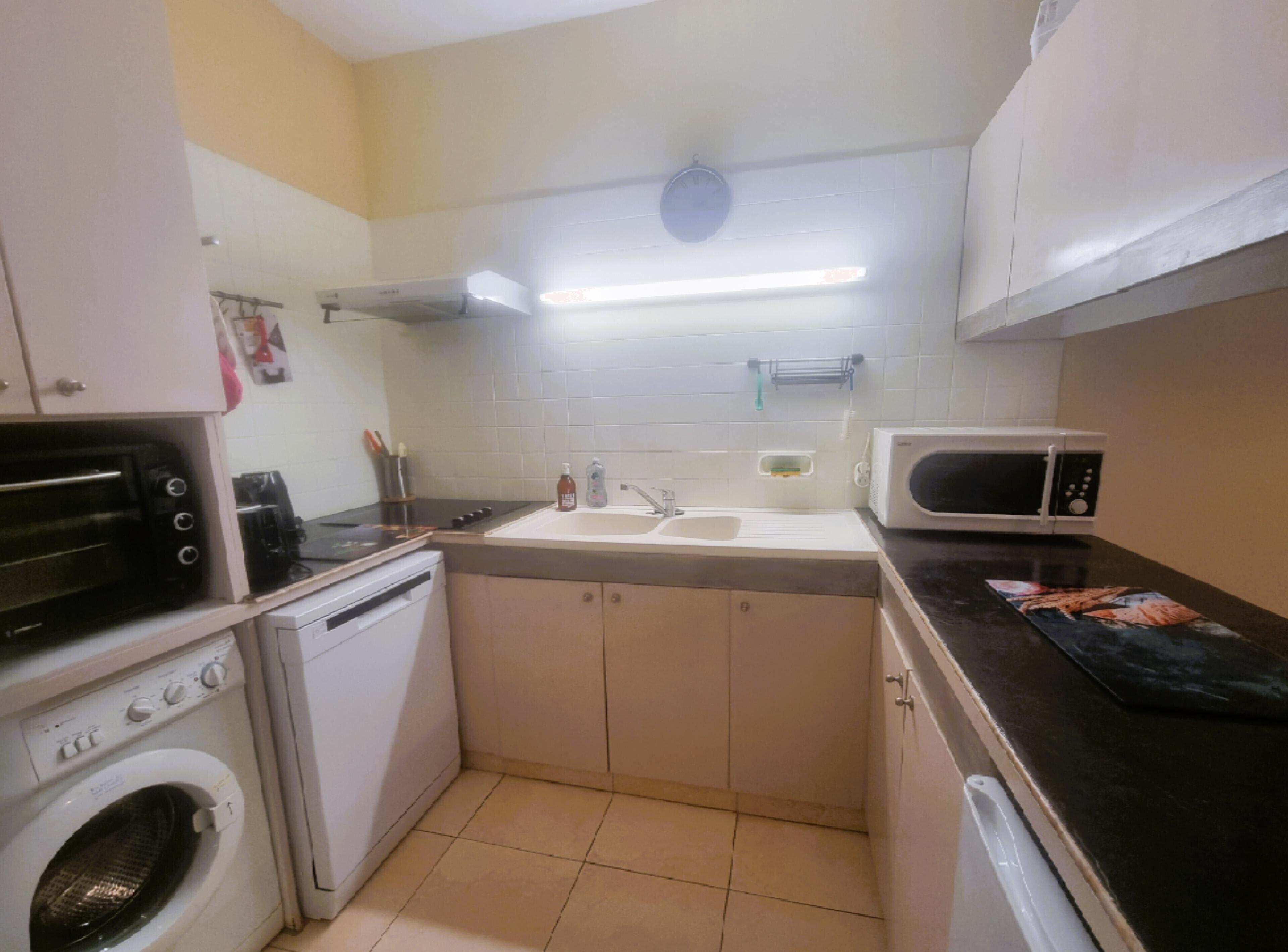 A compact kitchen with a washing machine, a microwave, and a sink.