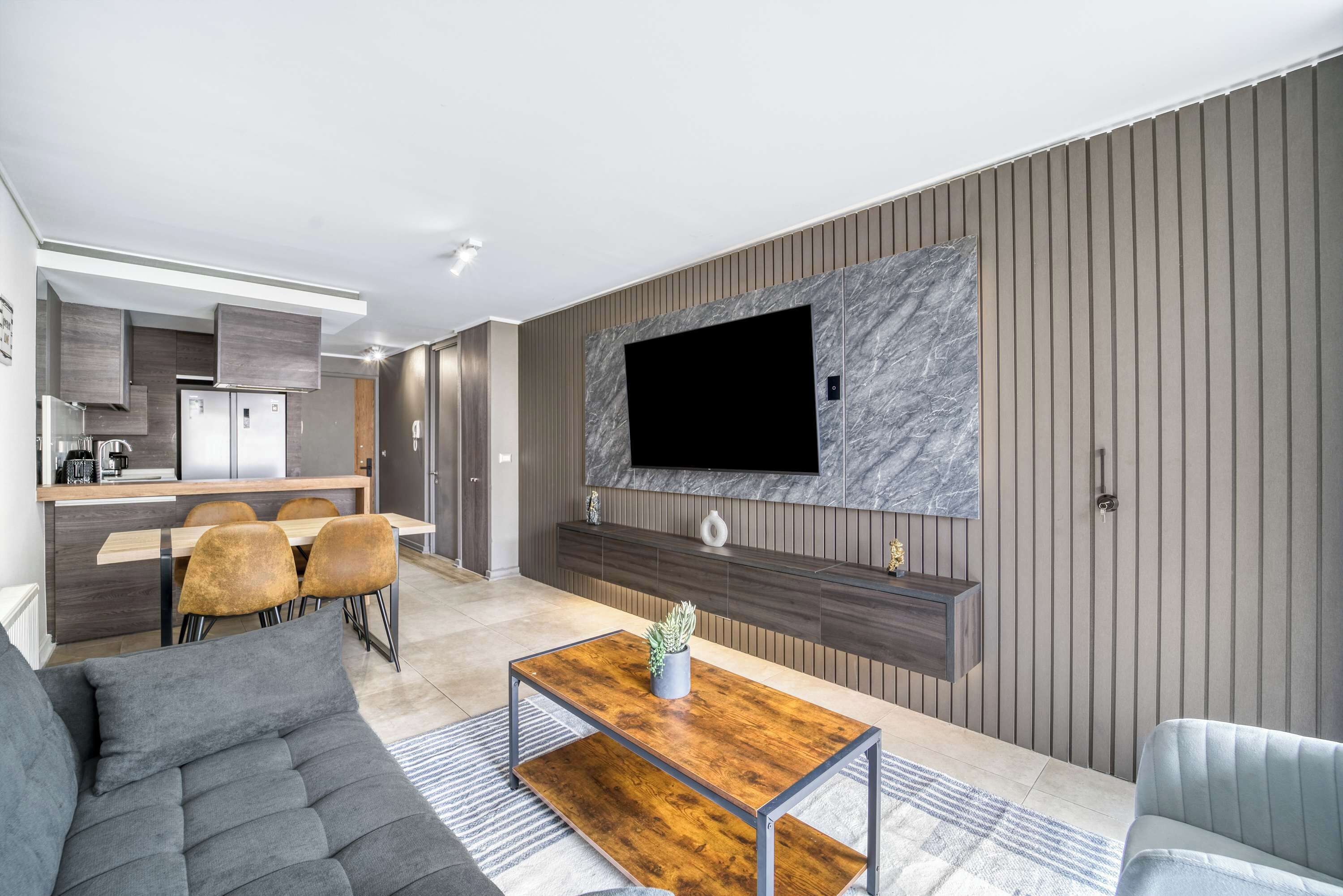 A modern living room with a sofa, a coffee table, and a TV mounted on a wall.