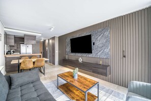 A modern living room with a sofa, a coffee table, and a TV mounted on a wall. - Eluchans One with Pool & parking near Reñaca Beach (Viña del Mar)