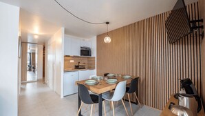 A modern kitchen with a dining area, featuring a wooden wall, a hanging light, and a coffee machine. - Bright apartment for 7 people in Les Deux Alpes (Les Deux Alpes)