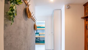 A hallway with a wooden bench, a coat rack with a woven bag, and a bunk bed in the background. - Bright apartment for 7 people in Les Deux Alpes (Les Deux Alpes)