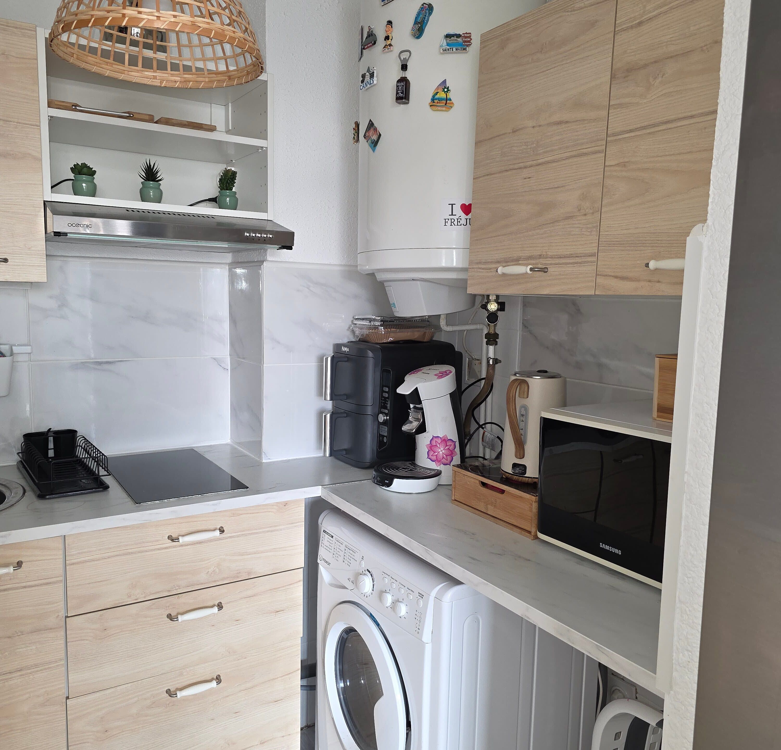 A compact kitchen with a built-in washing machine, a coffee maker, and a microwave.