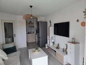 A modern kitchen with a built-in oven, microwave, and refrigerator. There is a dining area with a white table and chairs. - Apartment with View and Terrace in Fréjus (Fréjus)