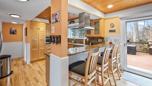 Een moderne keuken met houten kastjes, een roestvrijstalen afzuigkap en een bar met barkrukken.
