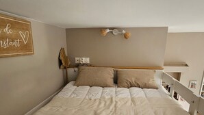 A bedroom with a bed, two pillows, a bedside table, a wall-mounted sign, and a lamp. - Bright studio apartment with terrace in Cannes (Cannes)