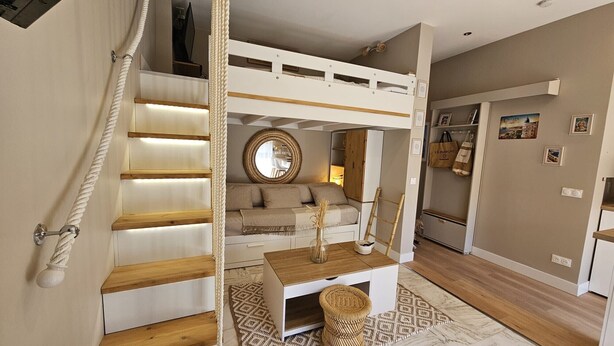 A bunk bed with a wooden ladder, a round mirror, and a small table with a vase. - Bright studio apartment with terrace in Cannes (Cannes)