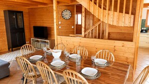 A wooden interior with a dining table set for six, a clock on the wall, and a staircase. - Apt or chalet near the slopes Les Orres (Les Orres)
